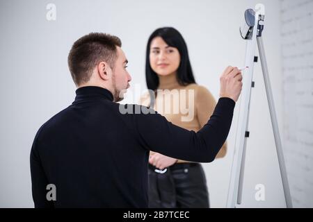 Der Typ, ein Geschäftsmann, ein Lehrer, ein Mentor, unterrichtet ein Fachmädchen, einen Schüler. Konzept des Arbeitstages Stockfoto