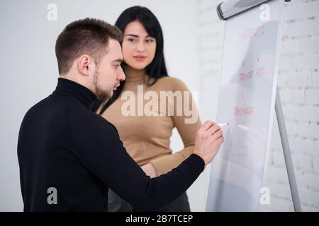 Der Typ, ein Geschäftsmann, ein Lehrer, ein Mentor, unterrichtet ein Fachmädchen, einen Schüler. Konzept des Arbeitstages Stockfoto