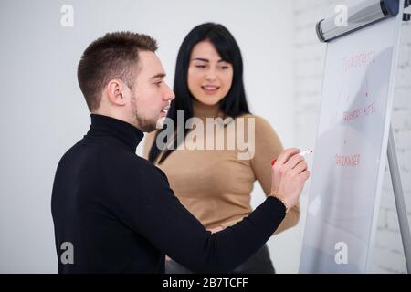 Der Typ, ein Geschäftsmann, ein Lehrer, ein Mentor, unterrichtet ein Fachmädchen, einen Schüler. Konzept des Arbeitstages Stockfoto