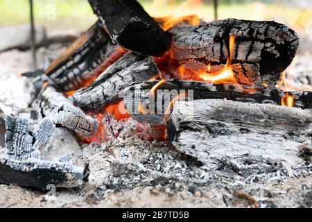 holzstämme oder Brennholz verbrennen mit rotgelber Flamme unter Glut- und lebenden Kohlen Stockfoto