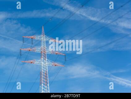 Abgewinkelte Ansicht eines roten und weißen Elektrizitätspylons mit blauem Himmelshintergrund. Stockfoto