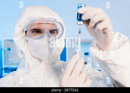 Selektiver Fokus des Wissenschaftlers auf Latexhandschuhe mit Spritze und Flasche mit Impfstoff Stockfoto