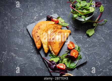 Lateinamerikanische, mexikanische und chilenische Küche. Traditionelle Backwaren Empanadas mit Rindfleisch auf dunklem Steingrund Stockfoto