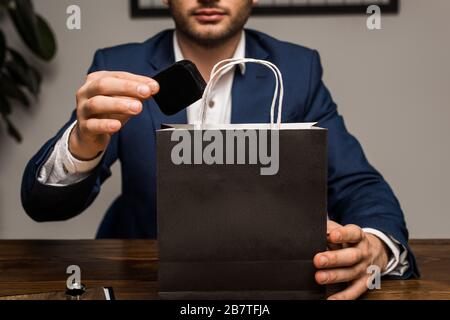 Beschnittener Blick auf die Schmucksachenschätzer, die die Schachtel in der Nähe der Papiertüte auf dem Tisch hält Stockfoto