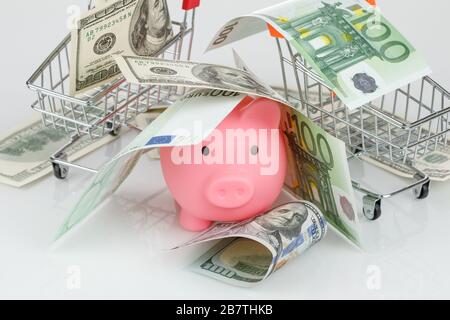 Pinkfarbene Spargelbox im Stapel von Dollar- und Euro-Banknoten auf grauem Hintergrund Stockfoto