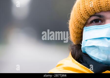 Nahaufnahme Portrait junge europäerin in schützender, medizinischer Gesichtsmaske, die draußen spazieren geht. Neues Coronavirus (COVID-19). Konzept des Gesundheitsautos Stockfoto