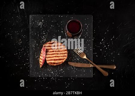 Gegrilltes wagyu-rind-Steak mit Rotwein, von oben auf schwarzem Hintergrund geschossen Stockfoto