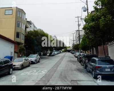 San Francisco, Kalifornien - Juli 2018: Abschüssige Straße mit Autos, die auf beiden Seiten vor Wohnhäusern geparkt sind. Stockfoto