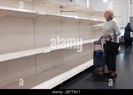 Eine Dame, die leere Regale in einem Sainsbury's Store in London betrachtet, als die Todesopfer von Coronavirus in Großbritannien 71 Menschen erreichte. Stockfoto