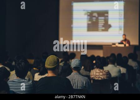 Rückansicht des asiatischen Publikums, der mit dem Sprecher auf der Bühne im Seminarkonferenzraum oder im Konferenzsaal, in der Ausbildung und im Workshop spricht, Stockfoto