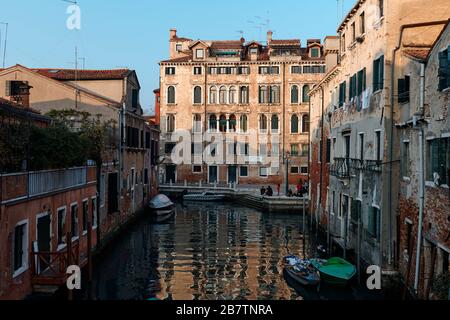 Venedig, Italien - 18. Februar 2020: Wasserspiegelungen am Kanal und im Hintergrund genießen die Menschen den sonnigen Tag Stockfoto
