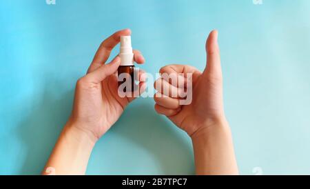 Eine Hand, die eine Sprühflasche mit der anderen Hand hält und eine gute Geste zeigt. Stockfoto