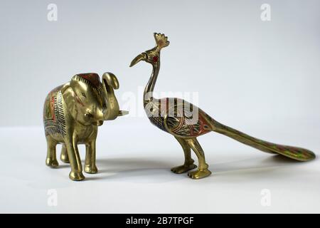 Kleine goldene Statuen von Elephant und Pfau auf weißem Hintergrund Stockfoto