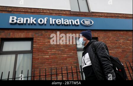 Ein Mann, der eine schützende Facemask trägt, läuft an einer Bank of Ireland Filiale in Dublin vorbei, während die CEOs der fünf Hauptbanken mit Finanzminister Paschalal Donohoe zusammentreffen sollen, um einen Plan zur Unterstützung der von dem Coronavirus betroffenen Kunden zu besprechen. Stockfoto