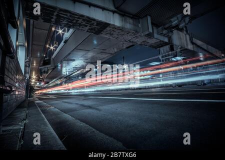 Blick auf den nächtlichen Verkehrsfluss unter einer erhöhten Autobahn in Namba, Osaka, Japan. Stockfoto