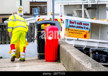 Der Ratsmann holt den Müllsack an der Küste in Sussex, Großbritannien Stockfoto