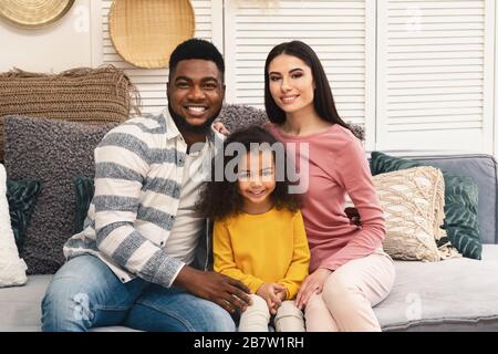 Lächelnde junge internationale Familie mit kleiner Tochter Stockfoto