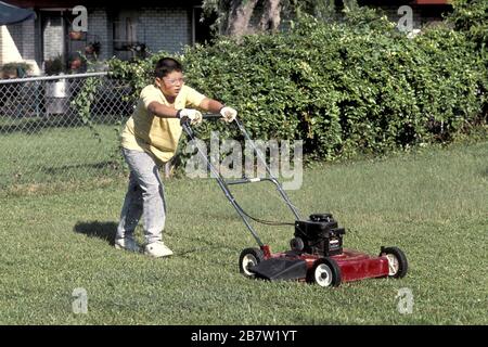 Austin, Texas USA,1988: Hispanischer Junge, 13, Rasenmähen mit gasbetriebenem Mäher. MR RR-0092. ©Bob Daemmrich Stockfoto