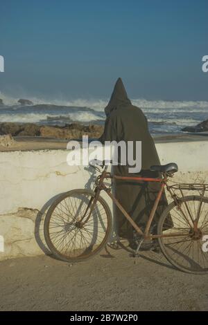 Lokaler Mann mit Blick auf das Meer am Strand am Atlantik in Essaouira, Marokko Stockfoto