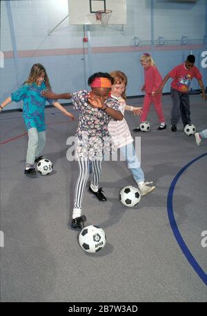 Austin, Texas USA: Schüler der fünften Klasse üben während der körperlichen Bildung im Fitnessstudio der Grundschule dribbelnde Fußballbälle. ©Bob Daemmrich / Stockfoto