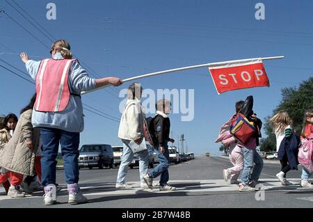 Austin, Texas, USA: Der Wachdienst für Erwachsene stoppt den Verkehr, während Schüler und Eltern die Straße vor der Walnut Creek-Grundschule überqueren. ©Bob Daemmrich Stockfoto