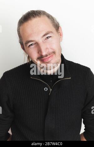 Studio-Porträt eines lächelnden jungen, erwachsenen Asiaten über weißem Wandhintergrund Stockfoto