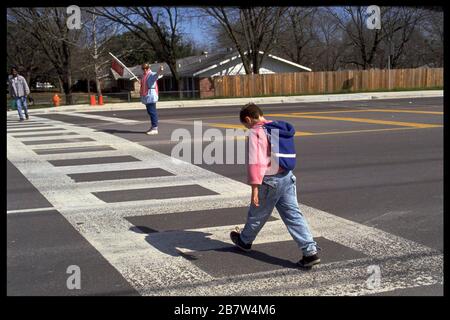 Austin, Texas, USA: Der Schulübergangswächter leitet Fußgänger und den Verkehr auf einem geschäftigen Fußgängerüberweg in der Nähe der Grundschule. ©Bob Daemmrich Stockfoto