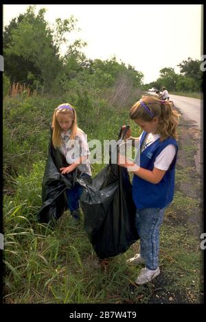 Junge Freiwillige sammeln Müll auf der Straße durch die Parklandschaft der Stadt. ©Bob Daemmrich Stockfoto