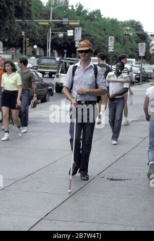 Austin, Texas, USA: Sehbehinderte Menschen nutzen einen weißen Stock, um sich auf einem belebten Bürgersteig in der Innenstadt zu bewegen. ©Bob Daemmrich Stockfoto