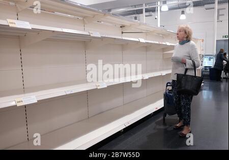 Eine Frau sieht sich leere Regale in einem Sainsbury's Store in London an, da Coronavirus weiterhin Großbritannien betrifft, wobei die Zahl der Todesopfer im Vereinigten Königreich 71 Personen erreicht. Stockfoto