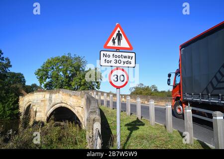 LKW, der keinen Fußraum für Fußgänger in vorausfahrender Straße passiert, Warnschild auf der Brücke, die den Fluss derwent in sutton auf derwent united überquert Stockfoto