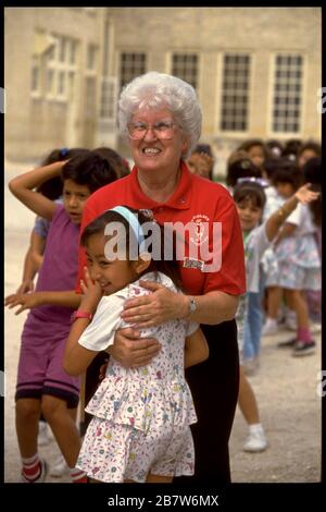 San Antonio, Texas USA: Grauhaariger Lehrer mit langjähriger Erfahrung umarmt Schüler im Schulhof. HERR ©Bob Daemmrich Stockfoto