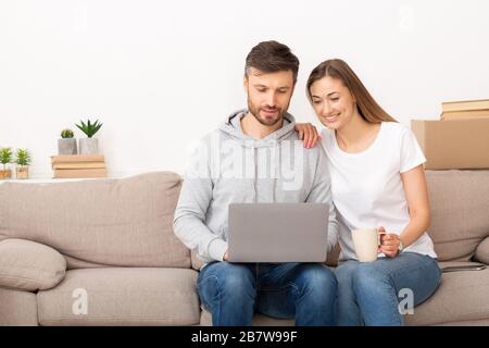 Junge Paare, die mit einem Laptop ein intelligentes Zuhause einrichten Stockfoto