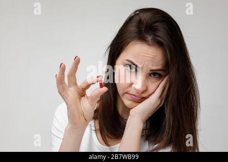 Junge traurige Frau mit Arznei, die unter Zahnschmerzen, Karies leidet. Mädchen mit Zahnschmerzen und Tablette. Konzept für Zahngesundheit und -Pflege Stockfoto