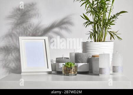 Tisch mit grüner Pflanze und saftigen Töpfen, teilweise in verschiedenen Größen und Farben Kerzen, leerem Bilderrahmen, Glas mit Holzdeckel und Kopierraum. Isolat Stockfoto