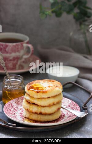 Käsekuchen, hausgemacht syrniki mit Honig und saurer Sahne. Stockfoto