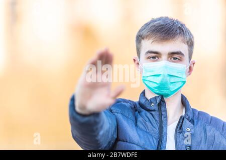 Junger Mann mit Schutzmaske, die Geste zeigt - stoppen Sie Coronavirus Kovid-19. Stockfoto