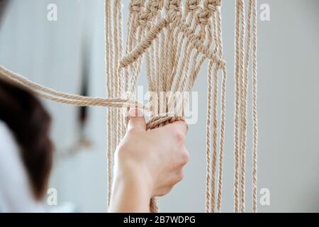 Die mittleren Knoten von Makrame. Mädchen bindet Knoten Stockfoto