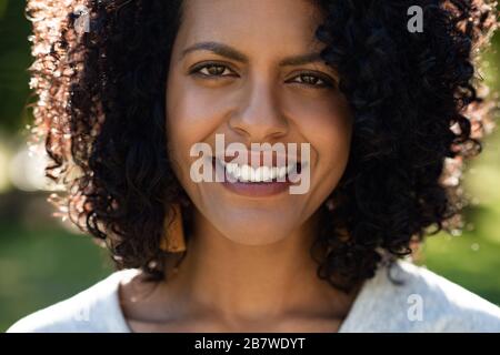 Junge Frau, die im Sommer draußen steht und lächelt Stockfoto