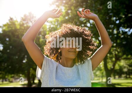 Junge Frau tanzt an einem sonnigen Nachmittag in einem Park Stockfoto