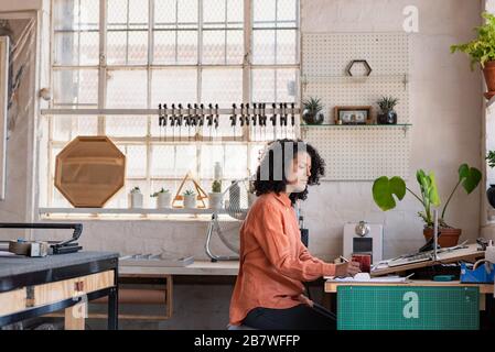 Junge Frau, die in ihrem Framing-Workshop an einem Schreibtisch arbeitet Stockfoto