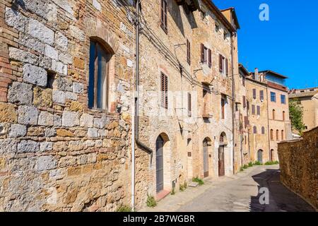 San Gimignano, Toskana / Italien: Eine ruhige Wohnstraße mit typischen Gebäuden im historischen Zentrum (UNESCO-Weltkulturerbe), am Morgen. Stockfoto