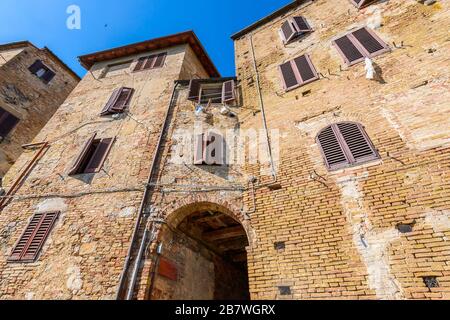 San Gimignano, Toskana / Italien: Eine ruhige Wohnstraße mit typischen Gebäuden im historischen Zentrum (UNESCO-Weltkulturerbe), am Morgen. Stockfoto