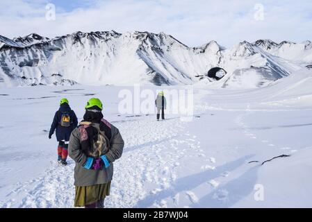 Besucher wandern auf dem Katla-Gletscher (Kötlujökull) in Südisland und gehen in Richtung einer Eishöhle im Tunnel, der in der Ferne zu sehen ist. Stockfoto