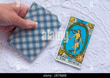 Hand Holding Rider Tarot Cards entworfen von Pamela Colman Smith unter der Aufsicht von Arthur Edward Waite mit der World Tarot Card gedreht Stockfoto