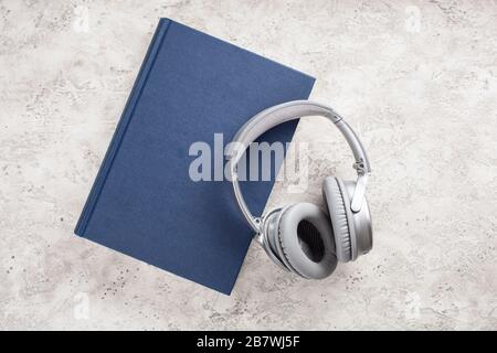 Hörbuchkonzept moderne drahtlose Kopfhörer und Buch Stockfoto