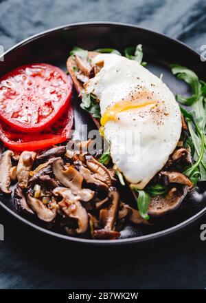 Sandwich mit frischen Arugula, gebratenem Shiitake-Pilz, Schalottenzwiebel, Ei serviert mit Tomaten. Stockfoto