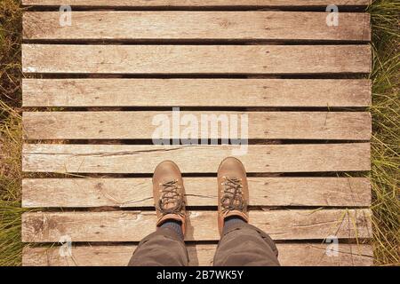 Wanderschuhe auf einem Holzsteg mit Kopierraum, Pov-Konzept, Vintage-Filtereffekt. Stockfoto