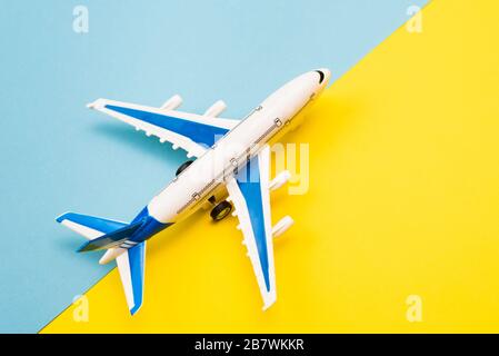 Online-Buchungs-Konzept. Flugzeugmodell und Reisepass auf gelbem und blauem Hintergrund. Abstrakte Landebahn. Stockfoto