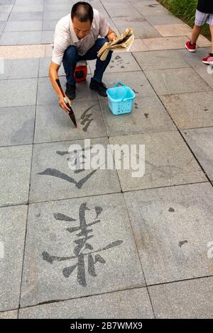 Mann, der dishu oder chinesische Boden Kalligraphie praktiziert, Xian, China Stockfoto